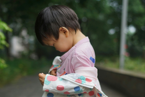 Child looking down wearing a coat with colooured spots Child looking down wearing a coat with colooured spots